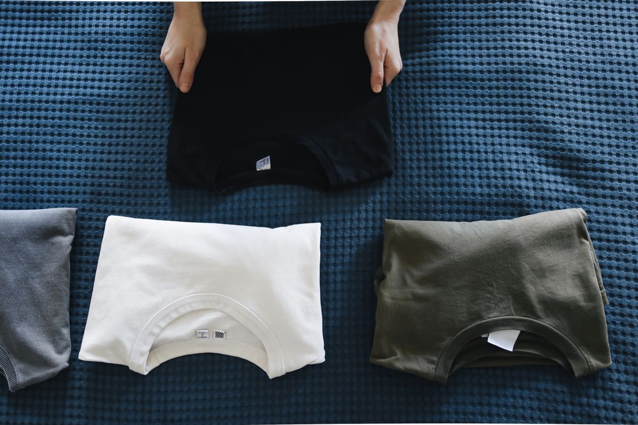Crafting Captivating Headlines: Your awesome post title goes here Top view of neatly folded colored T-shirts laid out on a blue bedspread, perfect for housekeeping themes.