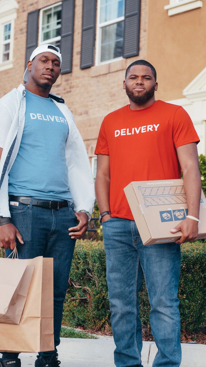 Mastering the First Impression: Your intriguing post title goes here Two delivery workers holding packages outside a residential building, showcasing modern commerce.